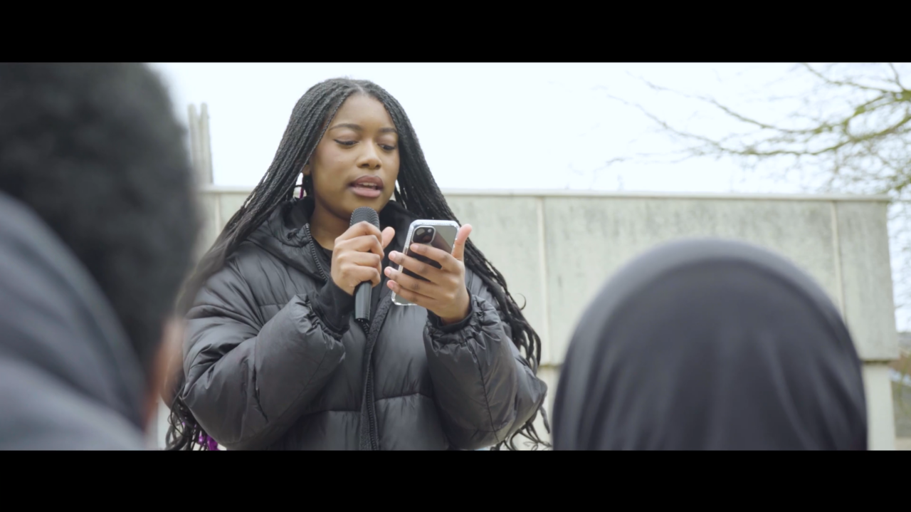 Femme noire parlant dans un micro devant une foule
